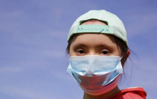 Girl in a mask on her face on background on a blue sky