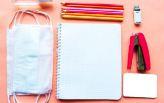 School supplies, white mockup notebook and medical mask on pink background. Back to school concept. School quarantine concept