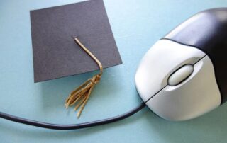 Closeup of a computer mouse and graduation cap - online education concept