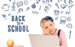 Schoolgirl sitting at a desk with a laptop. Background has many school-themed images drawn by hand