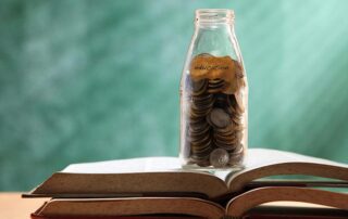 Savings jar filled with coin on top of books in a classrooom