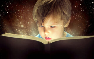 A young little boy reading a magical book with glowing stars, planets and galaxies floating out of it