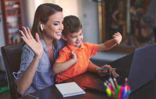 Mother and son smiling and waving to the camera on the laptop