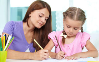 Mother and young girl drawing in a lined school notebook